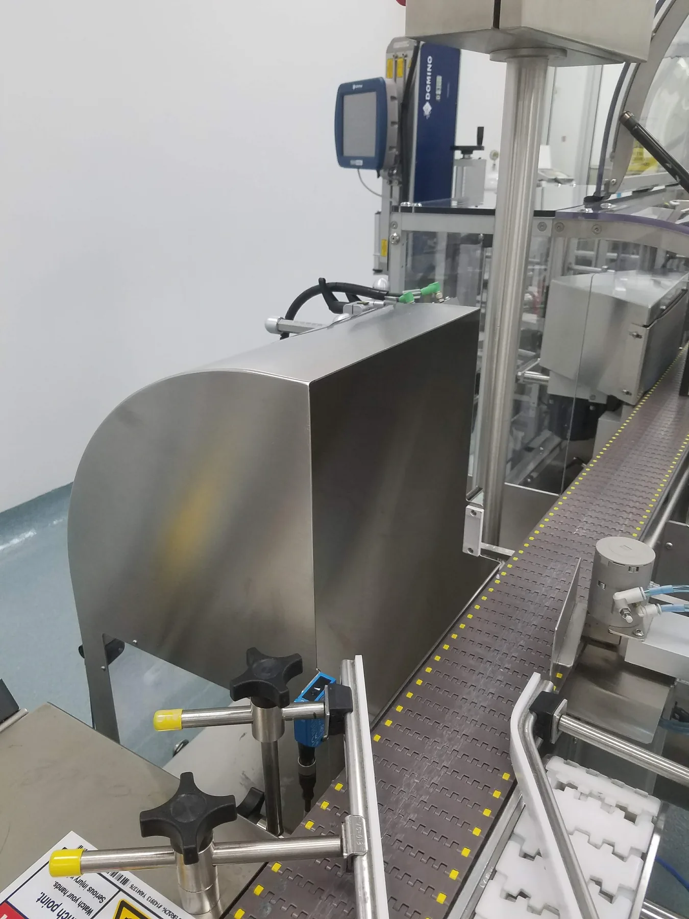 Stainless steel process equipment installed beside a conveyor